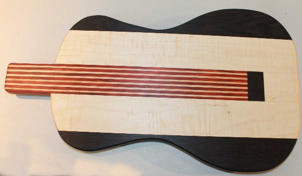 Black and blonde guitar shaped cutting board with red 'strings'