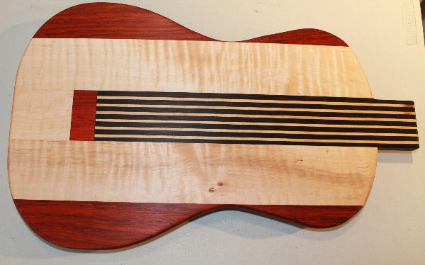 Red and blonde guitar shaped cutting board with black 'strings'