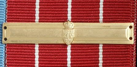 Gold Canadian Forces Decoration bar sitting on top of the red ribbonw ith white stripes.
