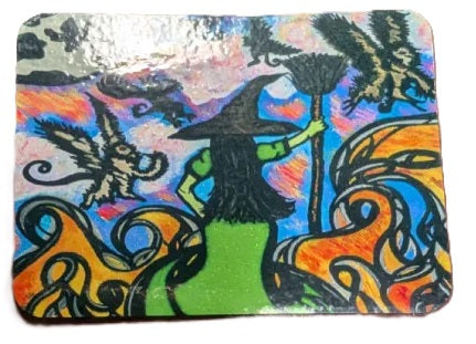 A square decorative art print or tile featuring a whimsical witch illustration with a green figure, black hat, broom, and swirling orange, blue, pink, and black abstract patterns on a white background.