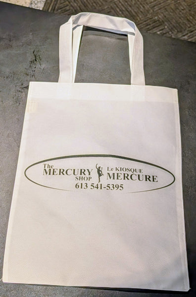 A white reusable tote bag with printed black text reading 'The Mercury Shop Le Kiosque Mercure' and a phone number, photographed on a dark gray surface.