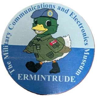 Circular badge with a cartoon duck in military uniform and text about the Military Communications and Electronics Museum.