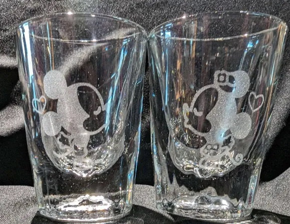 Pair of shot glasses with Mickey and Minnie Mouse facing each other to kiss