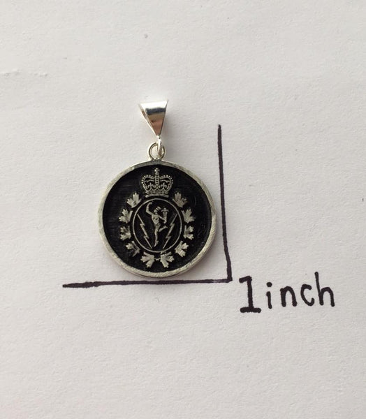 Round  sterling silver pendant charm with the C&E crest embosses within a ring of black oxidation. Text beside it shows that the charm is 1 inch in size