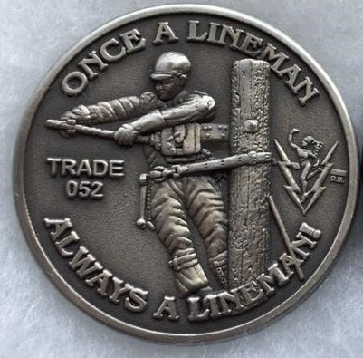 "Once a Lineman Always a Lineman" coin with "trade 052" and lineman on a pole graphic, in the one corner is the mercury with bolts.