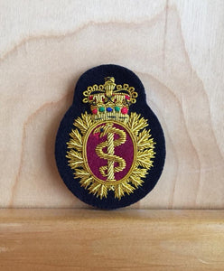 Cloth hat badge with medical crest with gold embroidery and snake.
