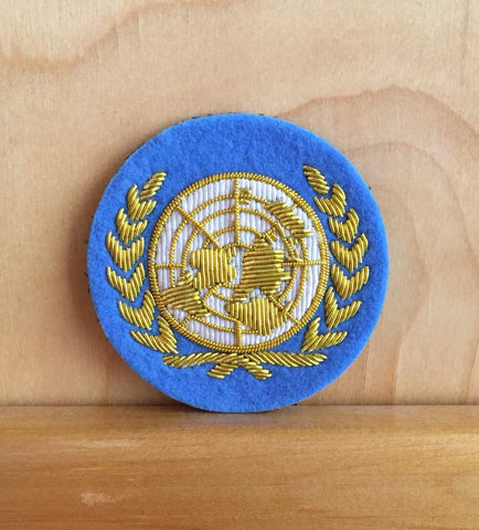Blue UN cloth capbadge with gold thread.