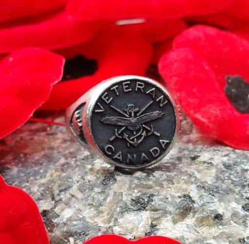 Silver ring with Canadian army crest surrounded by words 'Veteran Canada'. There is a maple leaf on the shoulder of the ring. The ring is surrounded by poppies.