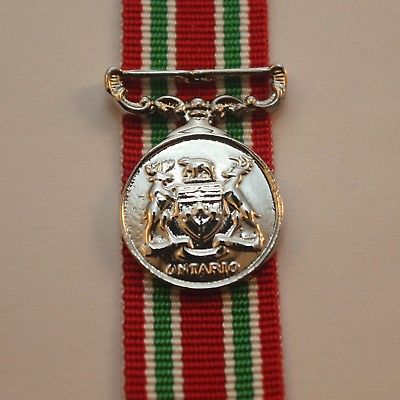 Front face of the silver Provincial Police Long Service and Good Conduct Medals sitting on top of the red, white, and green ribbon.